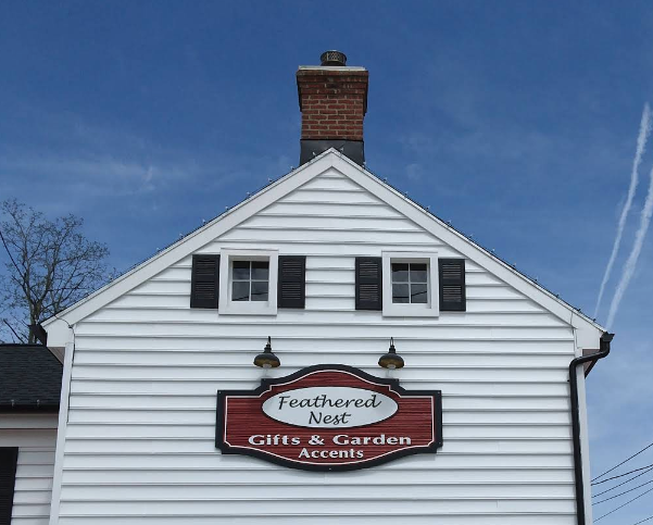 Feathered Nest Gifts & Garden Accents shop sign on the white shop building