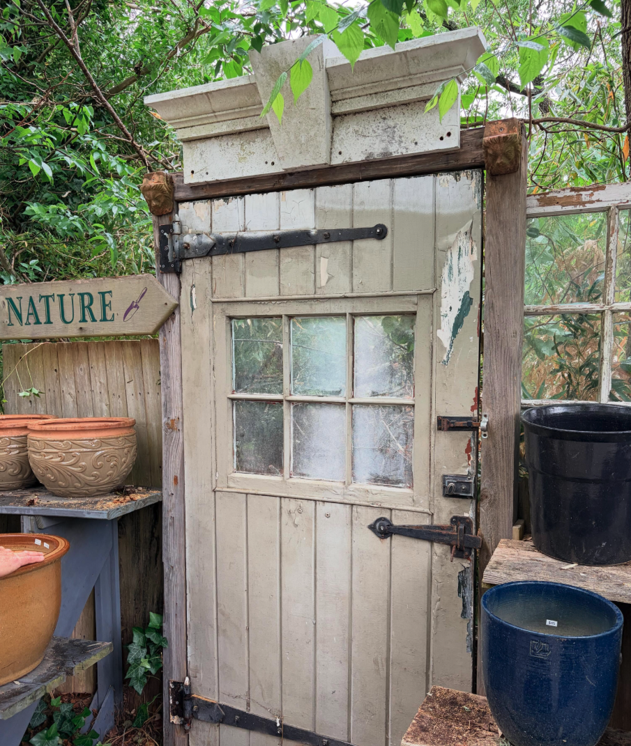 Rustic garden door surrounded by pottery and greenery at Feathered Nest